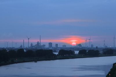 Blaue Weser, blaue Wolkendecke und rot untergehende Sonne über Bremen-Nord