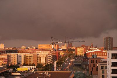 Von der Sonne angestrahlte Gebäude der Überseestadt mit dunklen Regenwolken