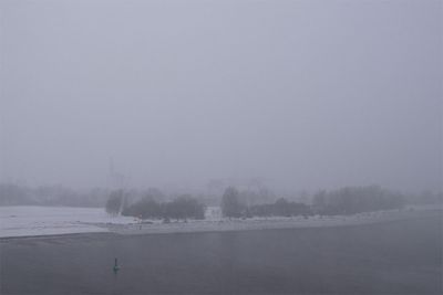 Schneebedecktes Ufer, Weser und Boje an diesigem Wintertag