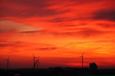 Silhouette von Windrädern und Gebäuden in Bremen, vor rotem Morgenhimmel