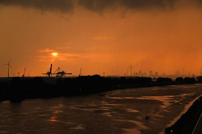 Segelschiff auf Weser, oranger Sonnenuntergang, Hafenkräne und Windräder