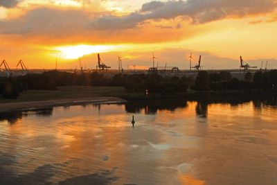 Sich in der Weser spiegelnder, goldener Sonnenuntergang mit Hafenkränen