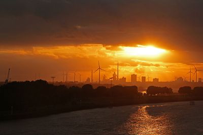 Weser, Windräder und Industrieanlagen vor orangefarbenem Sonnenuntergang