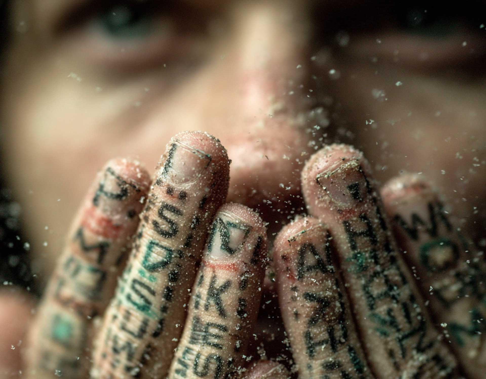 Eine Frau hält sich die mit Wörtern beschriebenen Hände vor den Mund